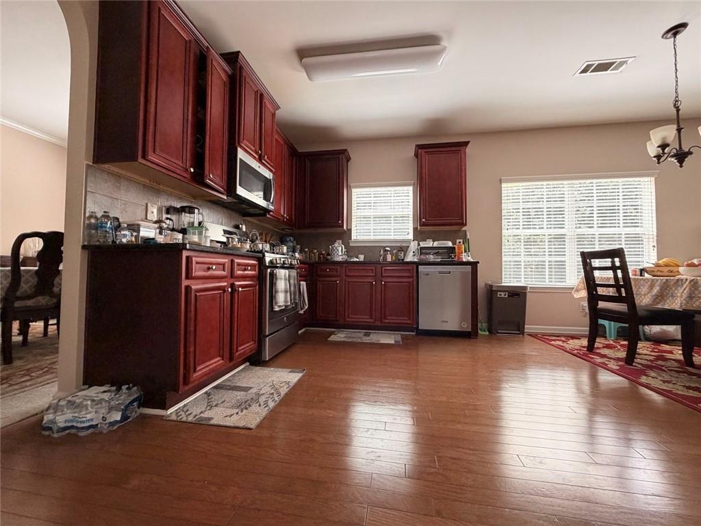 4080 Kittery Point Southwest Snellville, GA 30039 - Photo 15 of 25 a kitchen with stainless steel appliances granite countertop a stove top oven a sink dishwasher and wooden cabinets with wooden floor