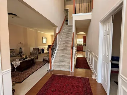 a view of a hallway to a livingroom with wooden floor and furniture