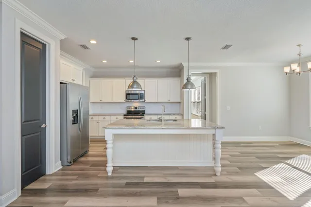 a kitchen with kitchen island white cabinets and stainless steel appliances