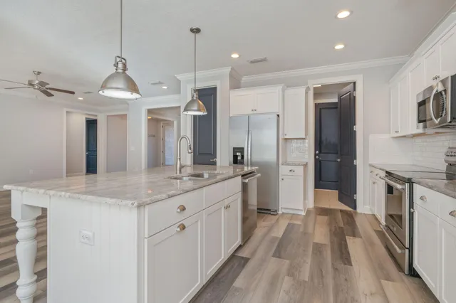 a large white kitchen with a sink and stainless steel appliances