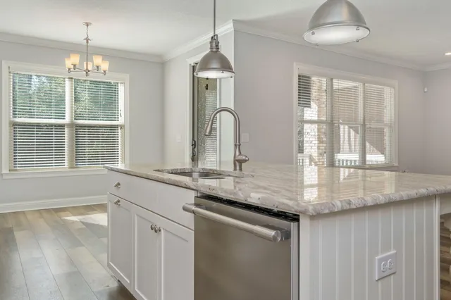 a kitchen with stainless steel appliances granite countertop a stove a sink and a large window