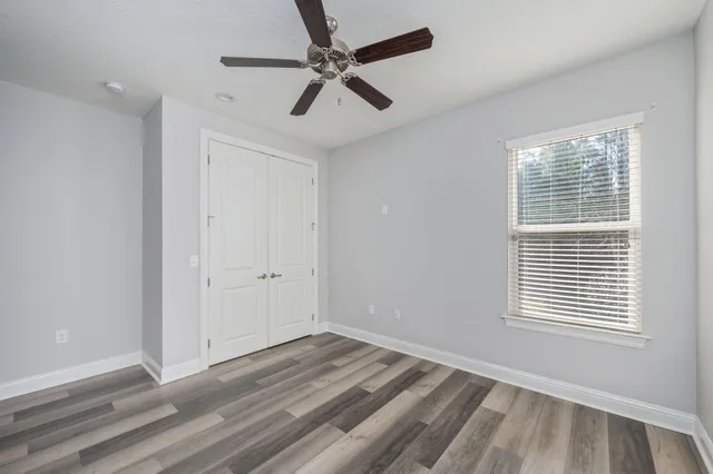 a view of empty room with wooden floor and fan