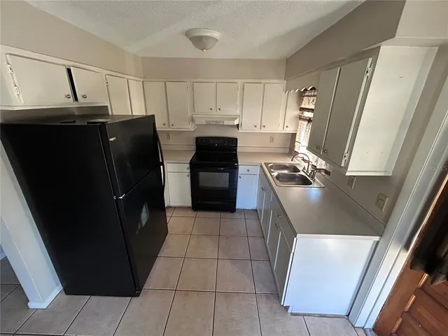 a kitchen with granite countertop a refrigerator and a stove top oven