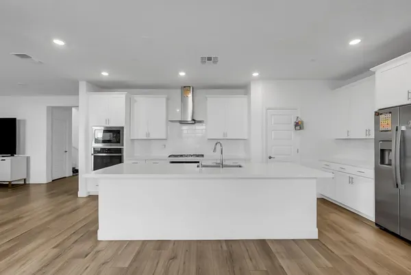 a kitchen with stainless steel appliances a stove top oven a sink a refrigerator and white cabinets