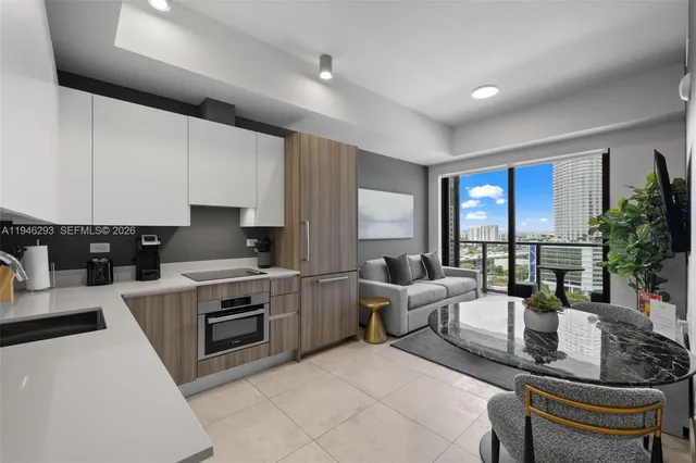 a living room with stainless steel appliances furniture a rug and a large window