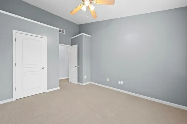 a view of an empty room with a chandelier fan