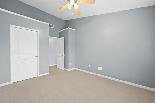 a view of an empty room with a chandelier fan