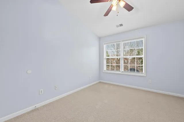 an empty room with a chandelier fan and windows