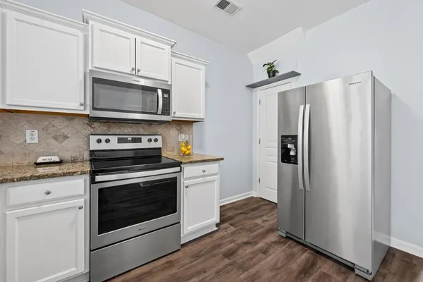 a kitchen with stainless steel appliances white cabinets white stove a refrigerator and a microwave