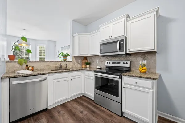 a kitchen with granite countertop white cabinets and white appliances