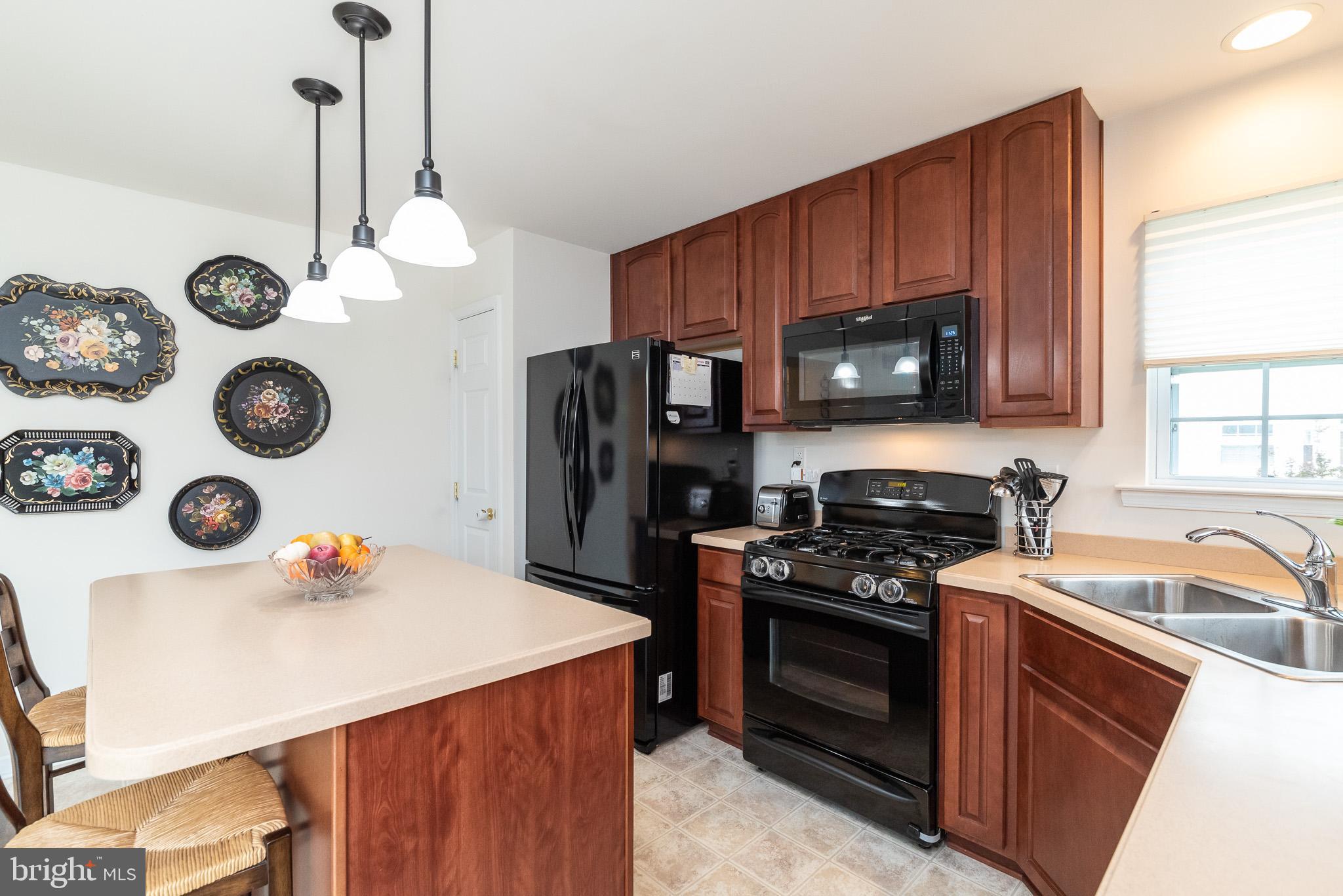 709 Walnut Grove Road Baltimore, MD 21221 - Photo 24 of 52 a kitchen with a refrigerator a stove a microwave and wooden floor