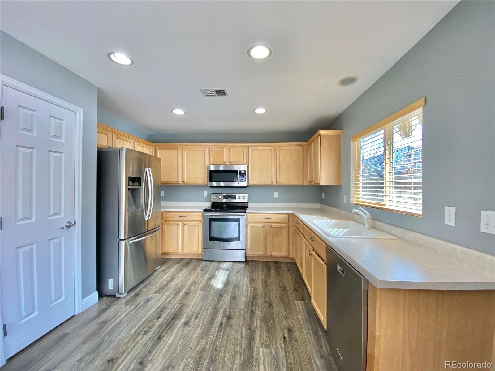 5731 Raleigh Circle Castle Rock, CO 80104 - Photo 2 of 16 a kitchen with stainless steel appliances granite countertop a refrigerator a sink dishwasher a stove and a oven with wooden floor