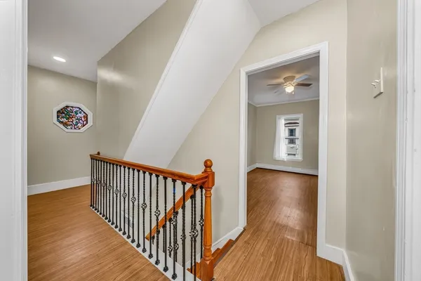 a view of a hallway with wooden floor and a bathroom