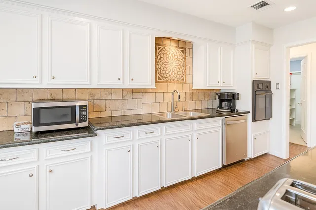 a kitchen with stainless steel appliances granite countertop a stove a sink and a microwave