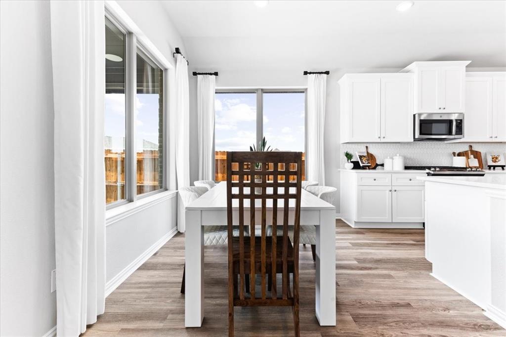 2339 Butler Avenue Fate, TX 75087 - Photo 11 of 35 a kitchen with stainless steel appliances granite countertop a stove top oven a sink and a dining table with wooden floor