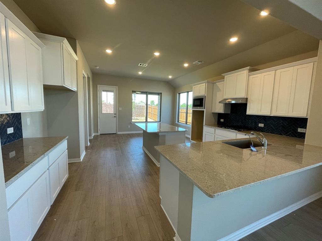 2339 Butler Avenue Fate, TX 75087 - Photo 25 of 35 a kitchen with stainless steel appliances granite countertop a sink a stove and a wooden floors