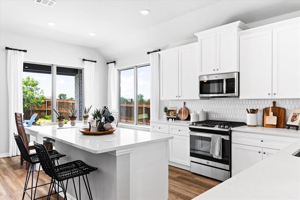 2339 Butler Avenue Fate, TX 75087 - Photo 6 of 35 a kitchen with stainless steel appliances a white table and chairs in it