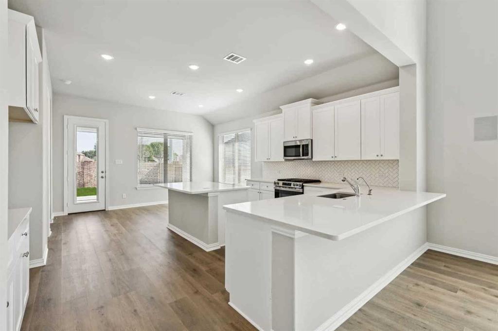 2339 Butler Avenue Fate, TX 75087 - Photo 9 of 35 a kitchen with stainless steel appliances a sink a stove a refrigerator cabinets and wooden floor