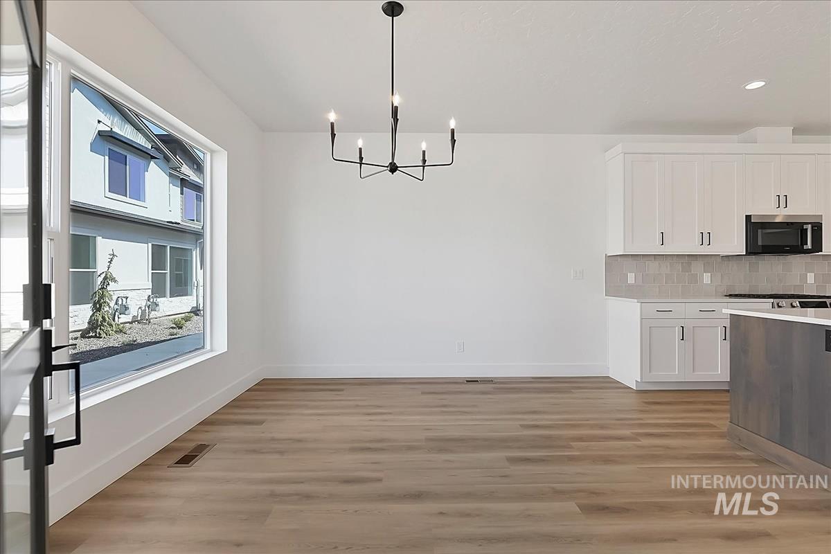 776 South Calhoun Lane Star, ID 83669 - Photo 17 of 49 Open-concept living space featuring wood-finish flooring, a large picture window, and a contemporary black chandelier