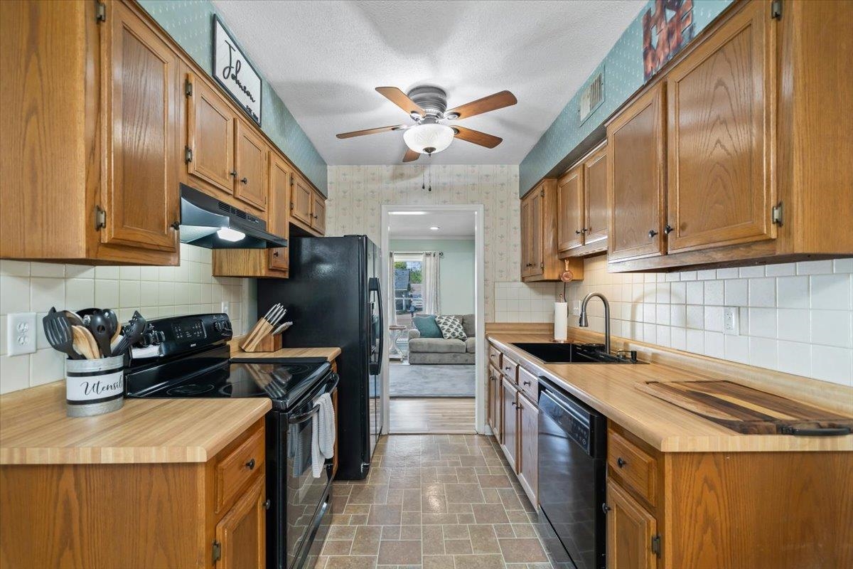 6315 Bardstown Road Bartlett, TN 38134 - Photo 13 of 31 Kitchen featuring black appliances, light countertops, wood finish cabinetry, wallpapered walls, and ceiling fan