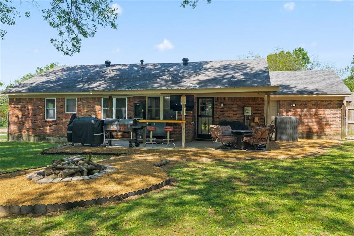 6315 Bardstown Road Bartlett, TN 38134 - Photo 29 of 31 Back of property with a fire pit, brick siding, a patio area, a lawn, and roof with shingles