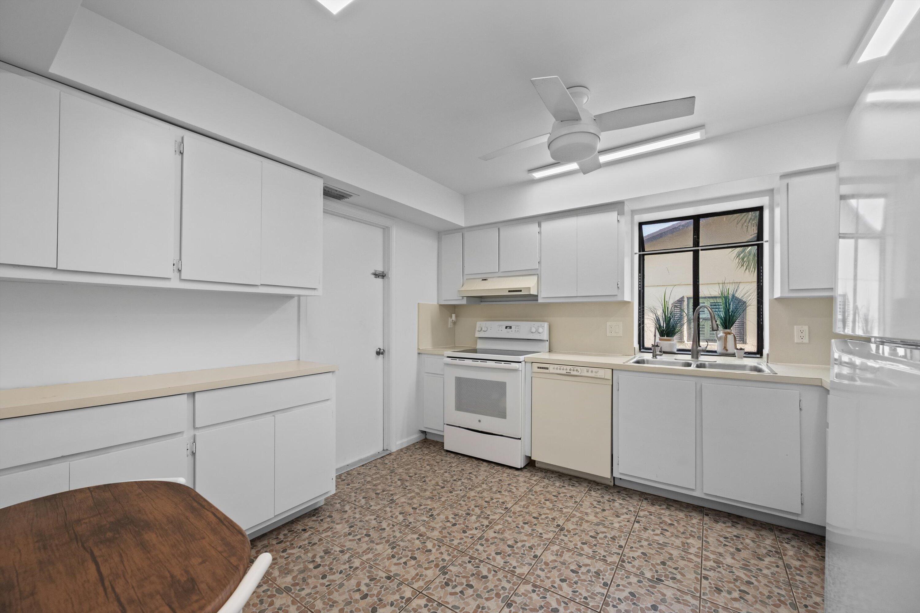 2 Ridge Pointe Drive, Unit A Boynton Beach, FL 33435 - Photo 5 of 24 a kitchen with white cabinets and white appliances