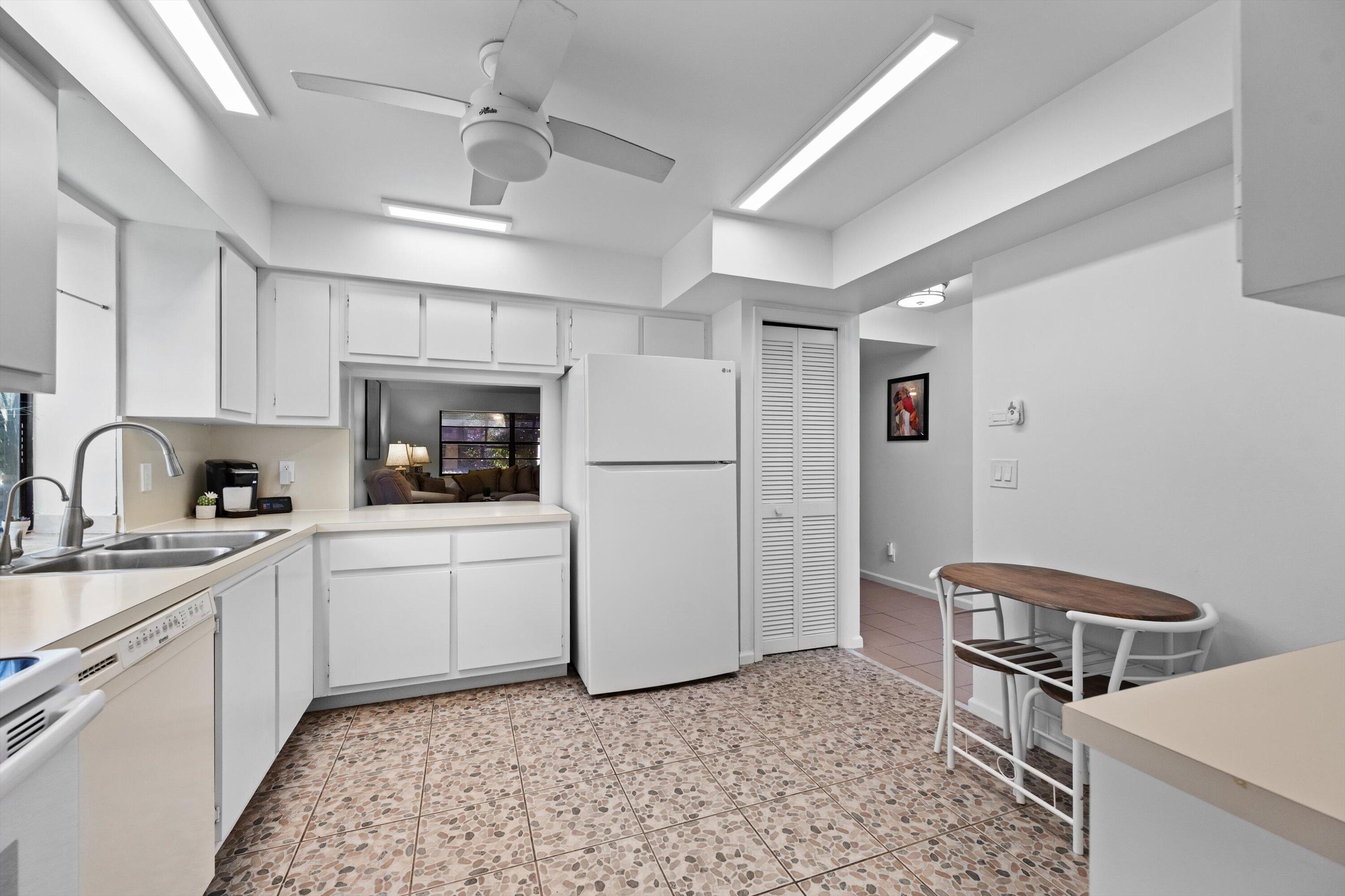 2 Ridge Pointe Drive, Unit A Boynton Beach, FL 33435 - Photo 6 of 24 a kitchen with a sink a refrigerator and cabinets