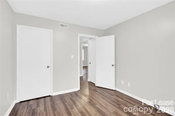 a view of an empty room with wooden floor and closet
