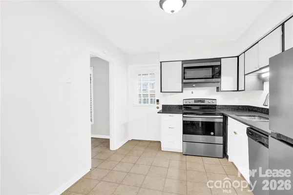 a kitchen with granite countertop a stove top oven and cabinets