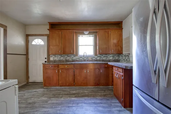 a view of granite countertop cabinets and refrigerator