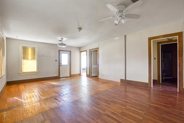 a view of an empty room with window and wooden floor