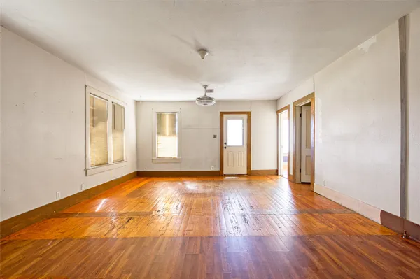 a view of an empty room with window and wooden floor