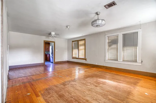 a view of an empty room with window and wooden floor