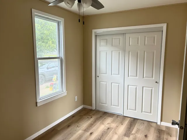 a view of an empty room with a window and wooden floor