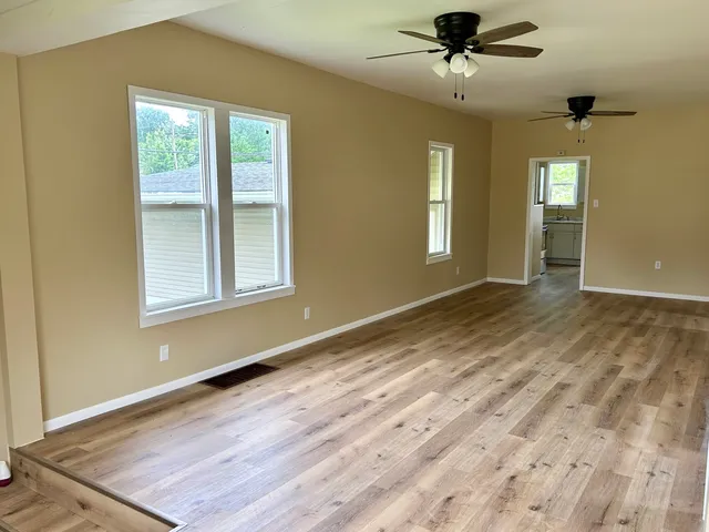 a view of an empty room with a window and wooden floor