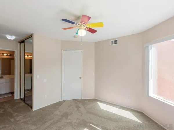 an empty room with window and ceiling fan