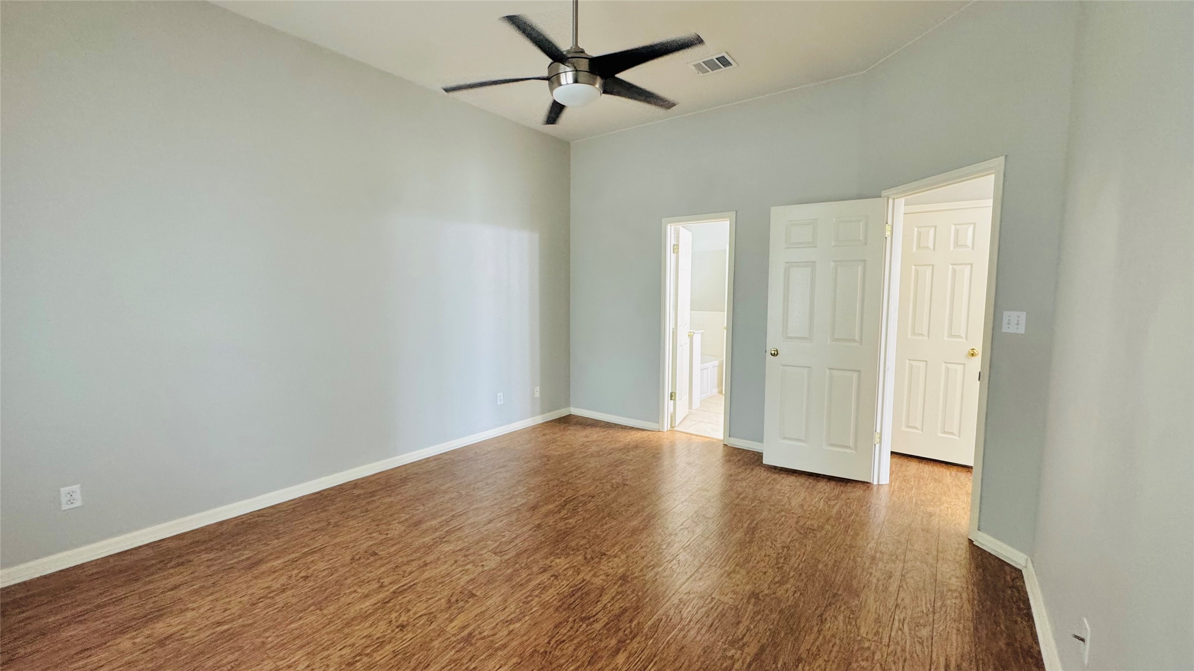 401 Witte Road Kyle, TX 78640 - Photo 9 of 24 Master bedroom-A vast bedroom, adorned with rich hardwood flooring and a stylish ceiling fan, offers a calm personal retreat.