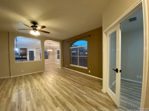 a view of empty room with wooden floor and fan