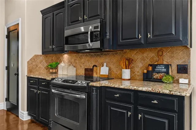 a kitchen with granite countertop stainless steel appliances a stove a microwave oven and cabinets