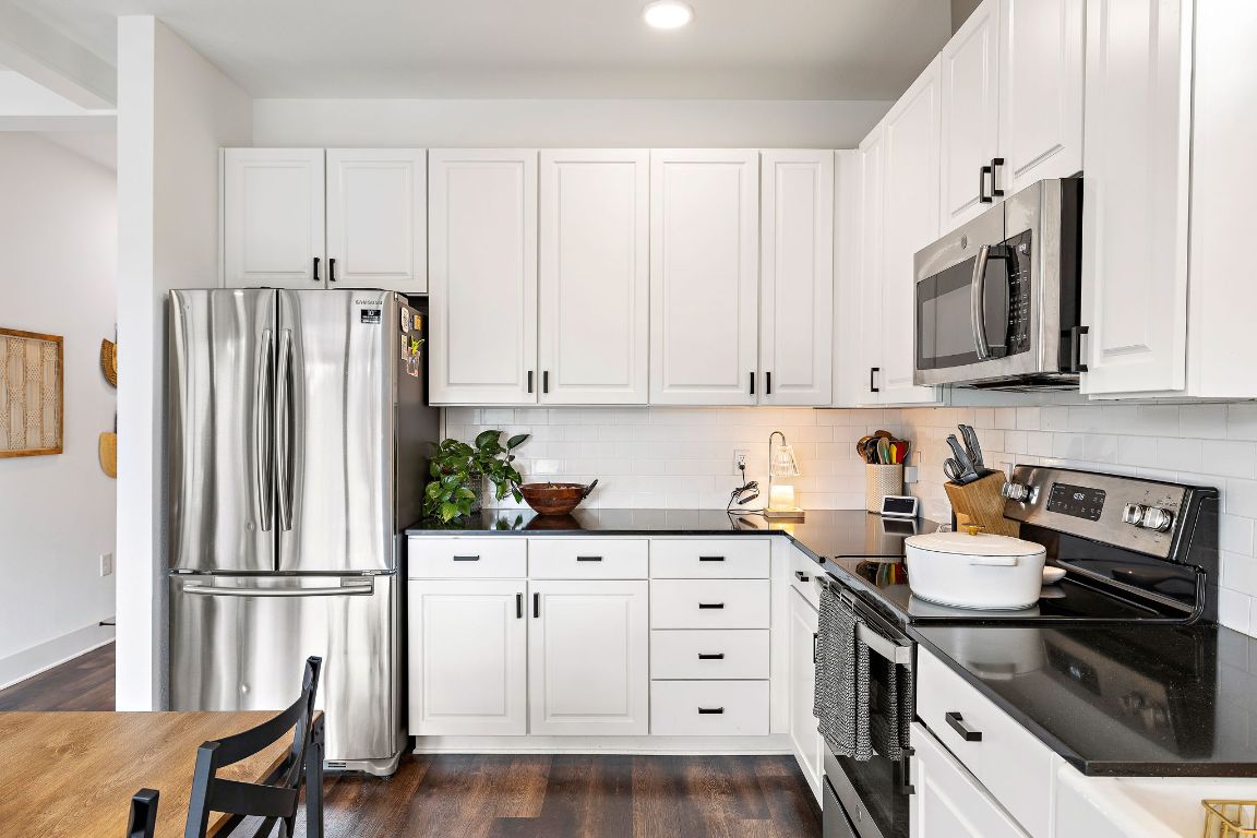 4704 Sunset Trail, Unit 1101 Austin, TX 78745 - Photo 11 of 23 Kitchen with appliances with stainless steel finishes, dark wood-style floors, white cabinets, backsplash, and recessed lighting
