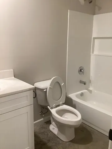 a white toilet sitting next to a bathroom sink and vanity