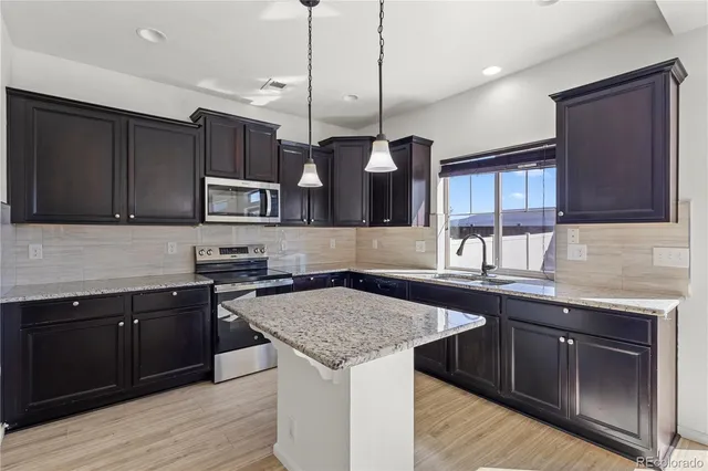 a kitchen with stainless steel appliances granite countertop a sink a stove and a microwave