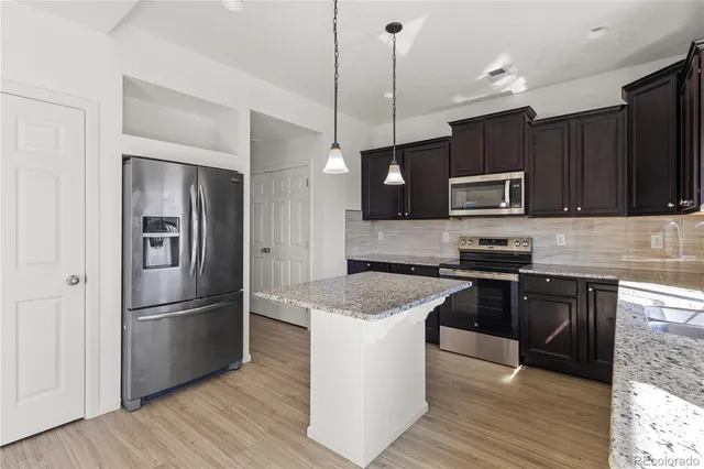 a view of a hallway to an empty room with wooden floor