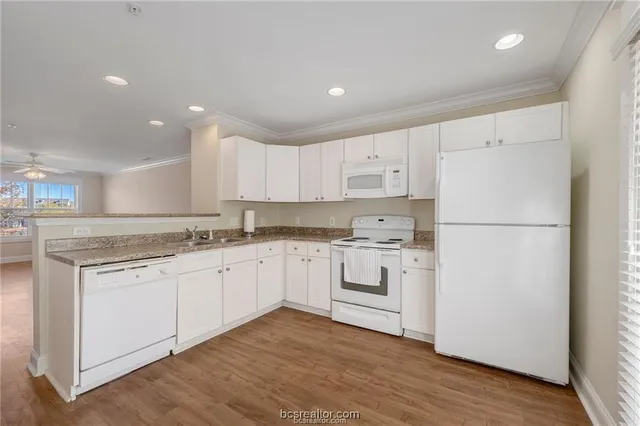 a kitchen with granite countertop white cabinets and white appliances