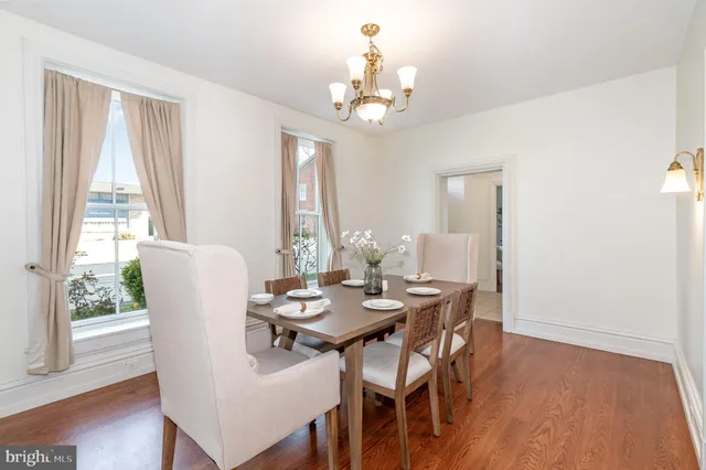 a dining room with wooden floor a chandelier a glass table and chairs