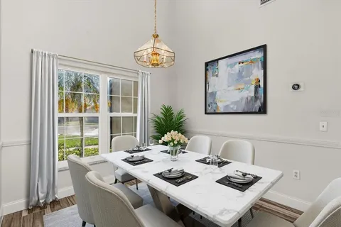 a view of a dining room with furniture a large window and a chandelier