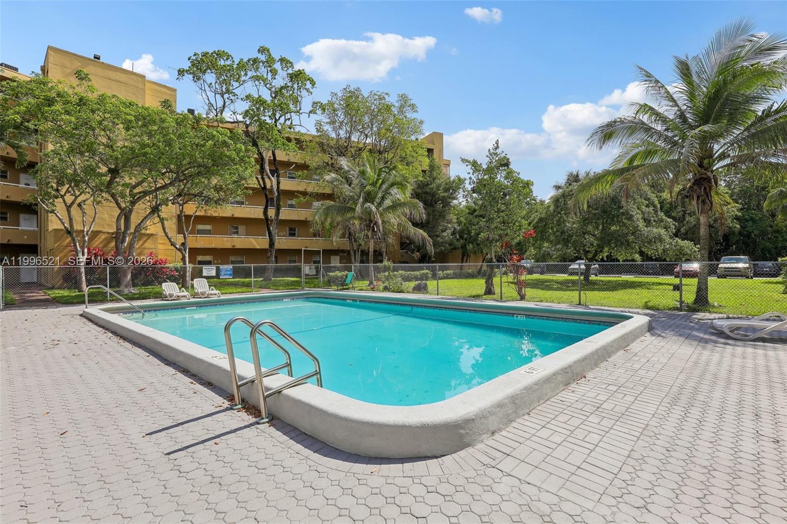 4137 Stirling Road, Unit 507 Dania Beach, FL 33314 - Photo 19 of 20 a view of a swimming pool with a yard and palm trees