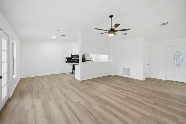 a view of empty room with wooden floor and ceiling fan