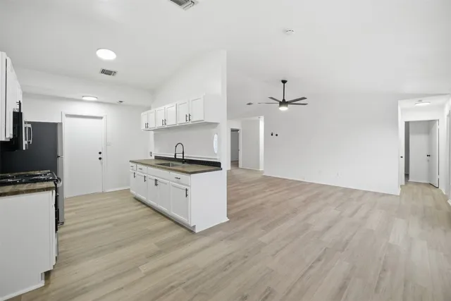 a kitchen with stainless steel appliances white cabinets and wooden floor