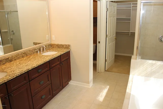 a bathroom with a granite countertop double vanity sink and a mirror